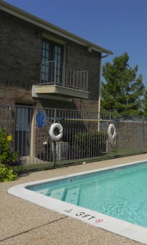 Sparkling swimming pool and building exterior with a private balcony at Highlands of Grand Prairie in Grand Prairie, Texas