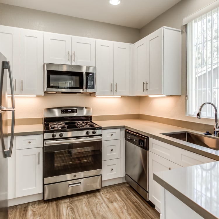 Modern kitchen with hardwood floors and stainless-steel appliances in a model home at Sofi Highlands in San Diego, California