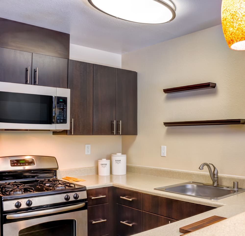 Stainless-steel appliances and rich, dark wood cabinetry in a model home's kitchen at Sofi Belmont Hills in Belmont, California