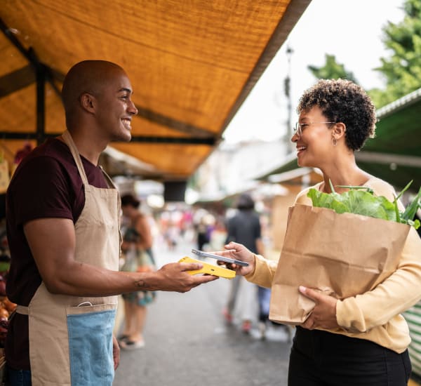 A smiling woman buying produce from a man outside near Heritage at Riverstone in Canton, Georgia