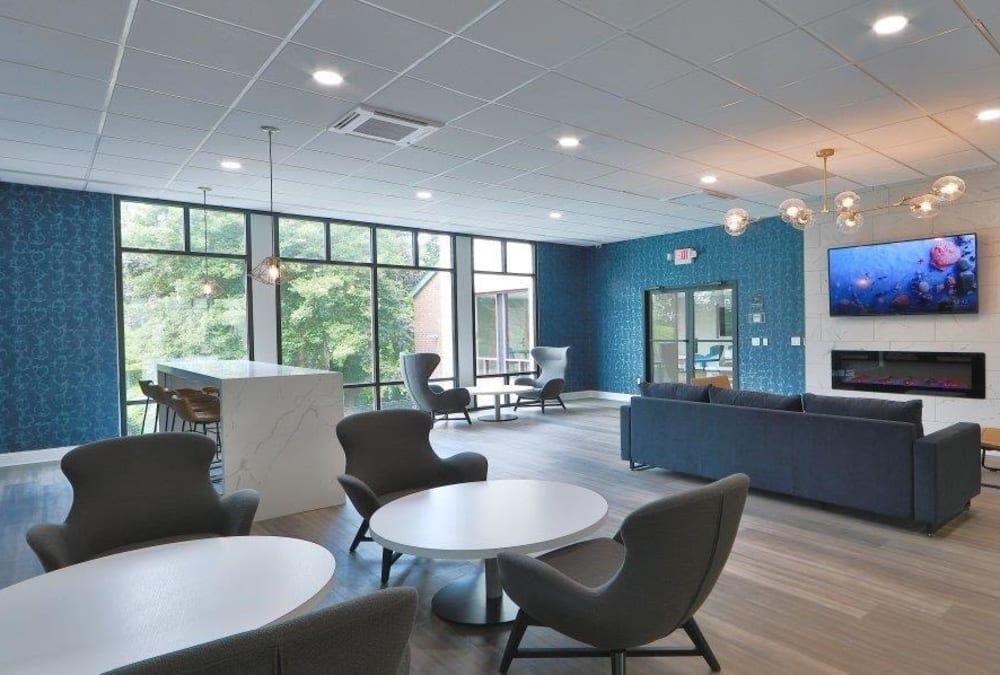 Resident lounge with a gas fireplace and large flat screen TVs at Stoneridge at Mark Center Apartment Homes in Alexandria, Virginia