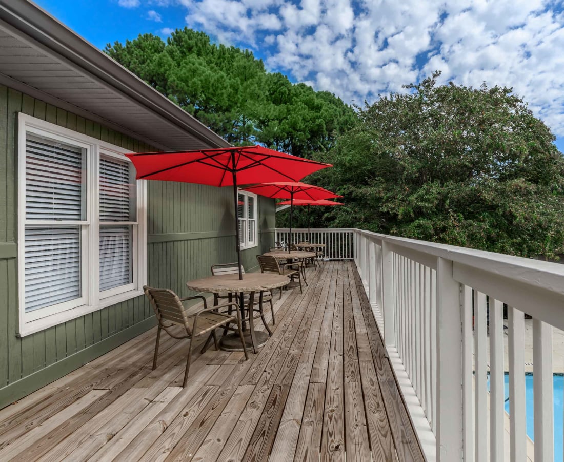 Umbrella-covered tables and chairs on a deck above the pool at Commons at Briarwood Park in Brookhaven, Georgia