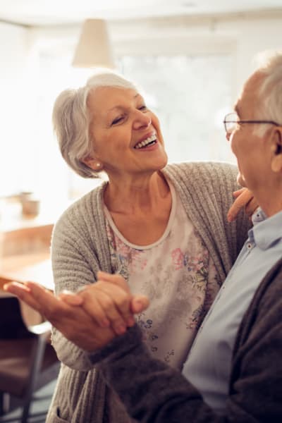 Senior couple dancing in their new apartment at a Quail Park Memory Care Residences of West Seattle community