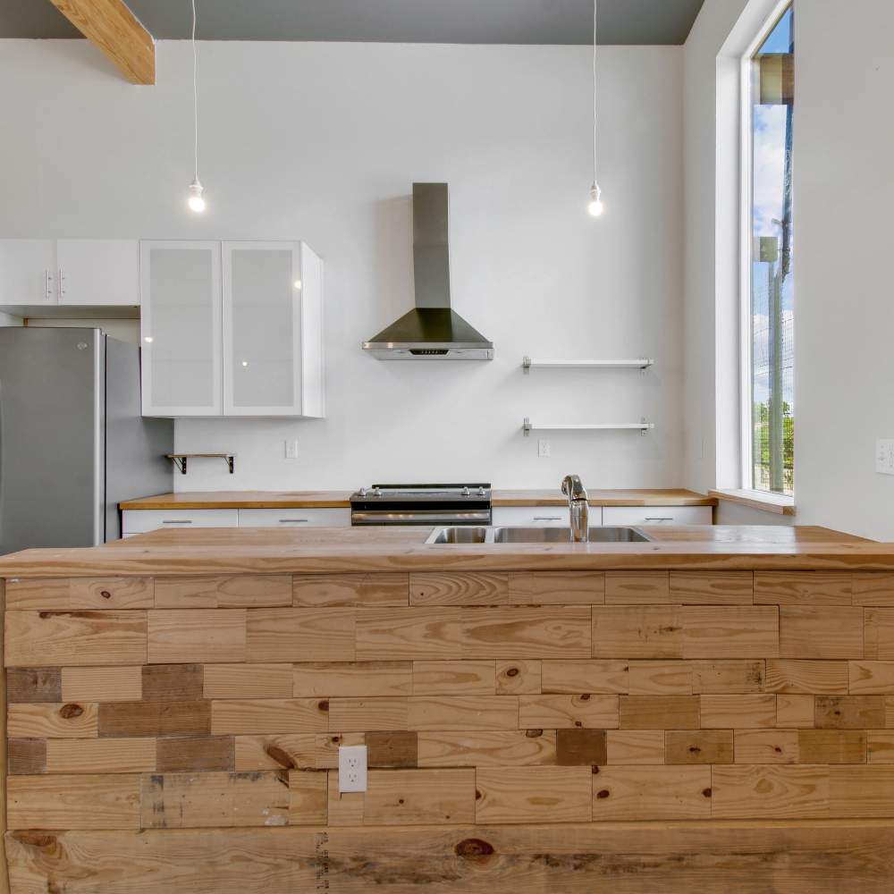 Modern kitchen with stove, sink, hood and refrigerator at The Lofts at 305 in Bryan, Texas