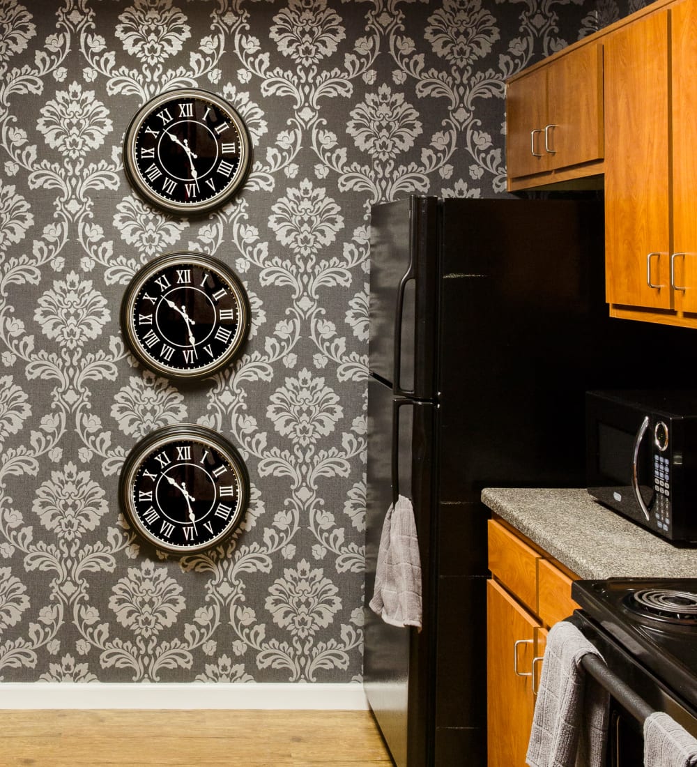 Kitchen with sleek black appliances and dramatic wallpaper at The Scarlet in Lubbock, Texas