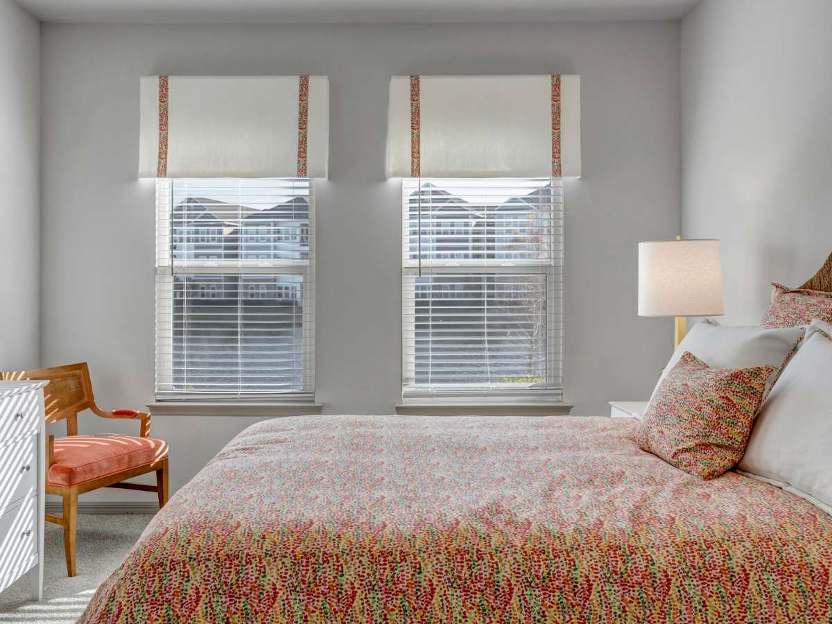 Bright bedroom with large windows, cozy chair, and colorful bedding on a comfortable bed at The Carlton of West Melbourne in West Melbourne, Florida