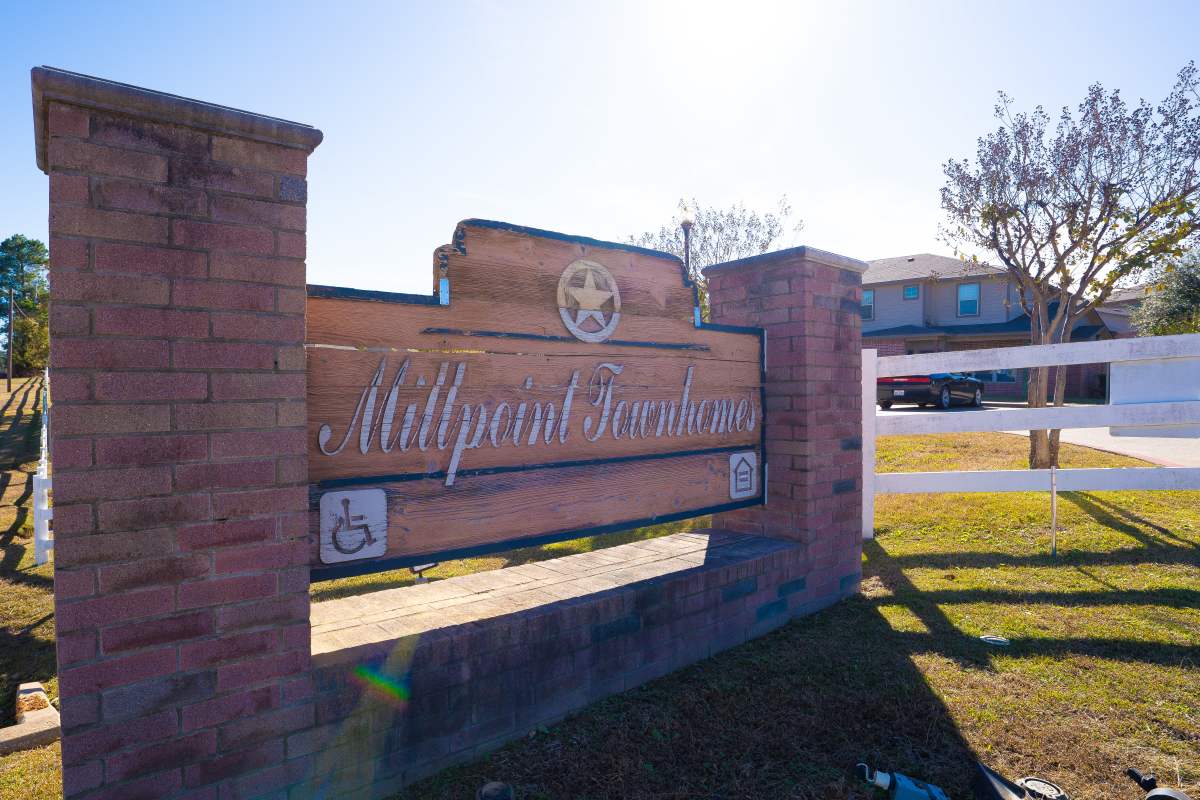 Community entrance with property signage board at Millpoint Townhomes in Henderson, Texas