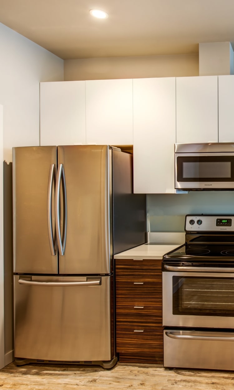 Modern kitchen with sleek, stainless-steel appliances and a dual-basin sink in a model home at Verse Seattle in Seattle, Washington