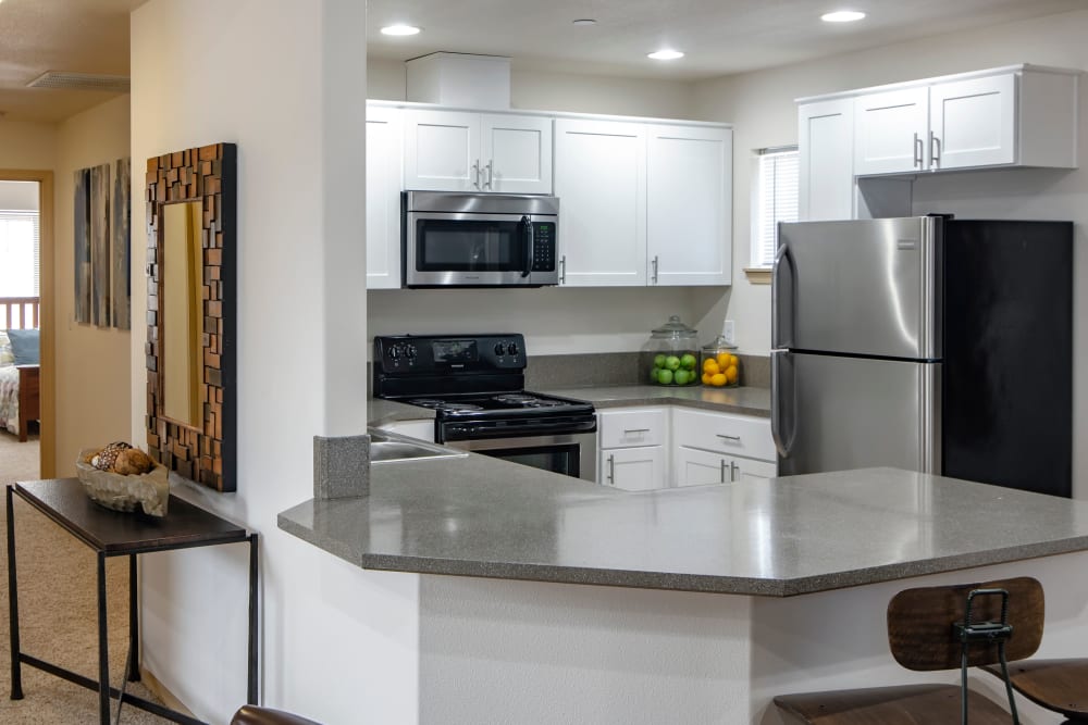 Renovated kitchen with white cabinetry and a hallway view at The Addison Apartments in Vancouver, Washington