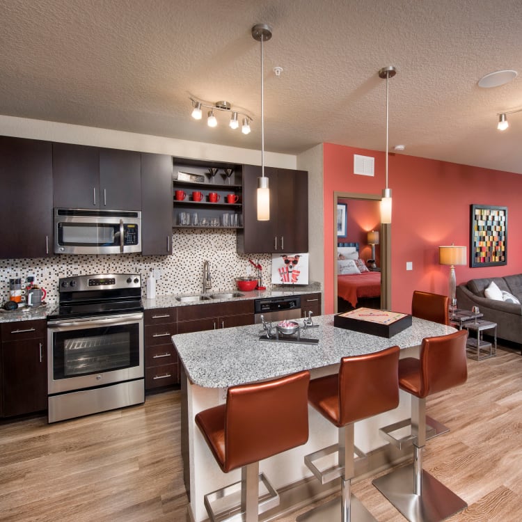 Gourmet kitchen with hardwood floors and an accent wall in the living area of a model home at The Courtney at Universal Boulevard in Orlando, Florida