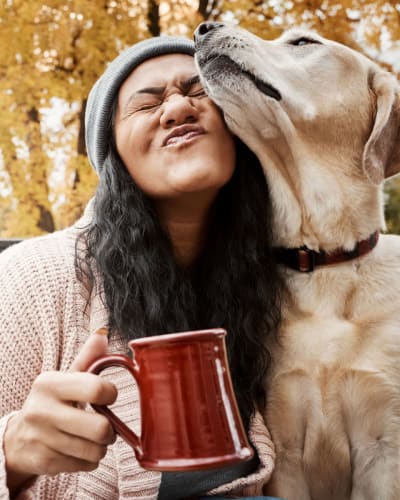 Resident enjoying her morning coffee and some love from her dog outside their new home at Vantage Park Apartments in Seattle, Washington