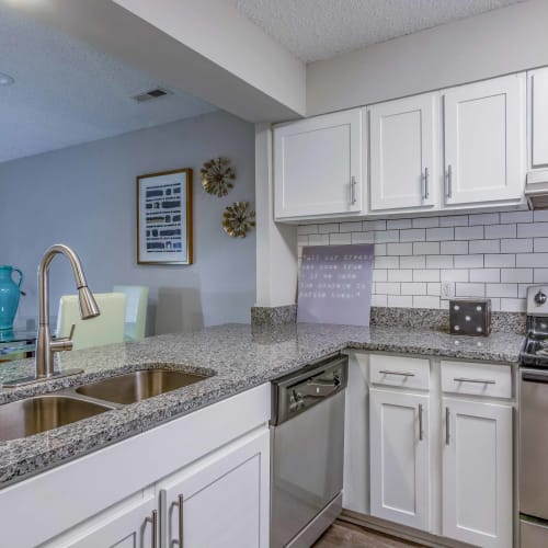 Granite countertops and black appliances in an apartment kitchen at Hickory Creek in Henrico, Virginia