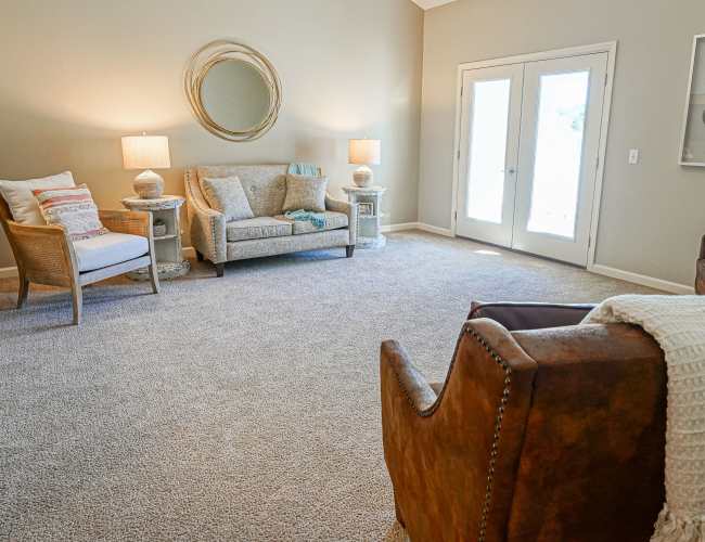 Living room with couch, chair and glass door leading to patio at Harmony at Harts Run in Glenshaw, Pennsylvania