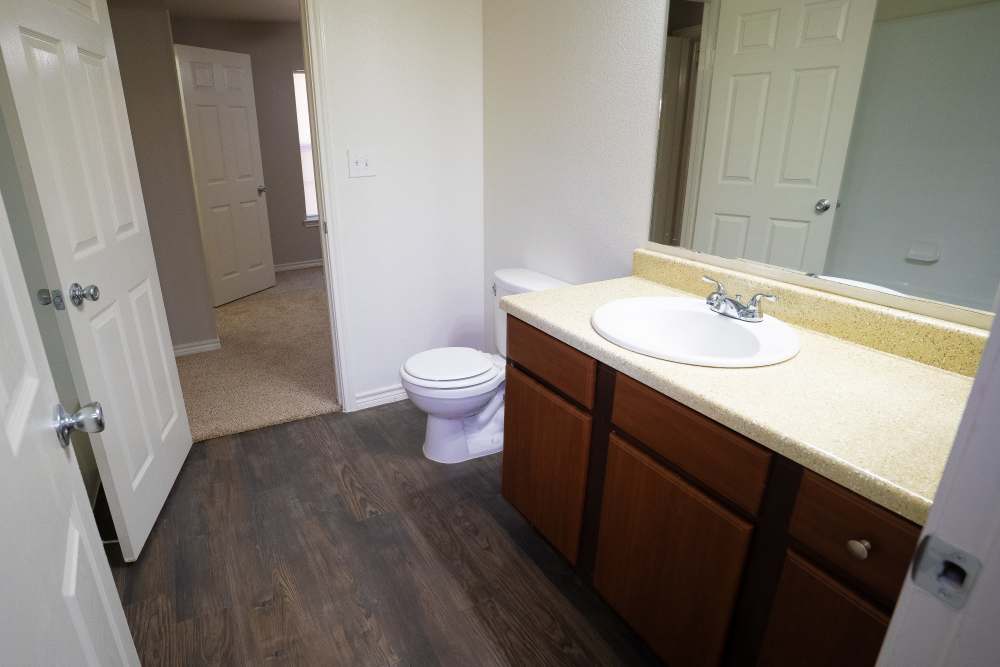 Bathroom with mirror, sink, commode and hard wood flooring at Timber Village II in Marshall, Texas