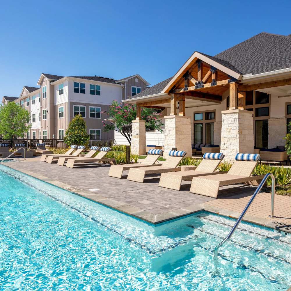 Resort-style pool at night with lounge chairs at August Friendswood in Friendswood, Texas