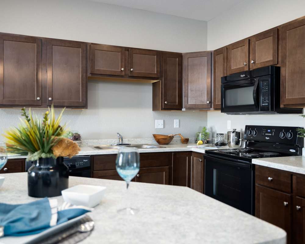 Kitchen with black appliances and wooden cabinets at University Commons in Williston, North Dakota