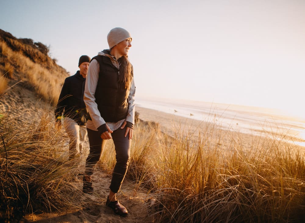 A couple takes a walk along a sandy beach near Serramonte Ridge Apartment Homes in Daly City, California