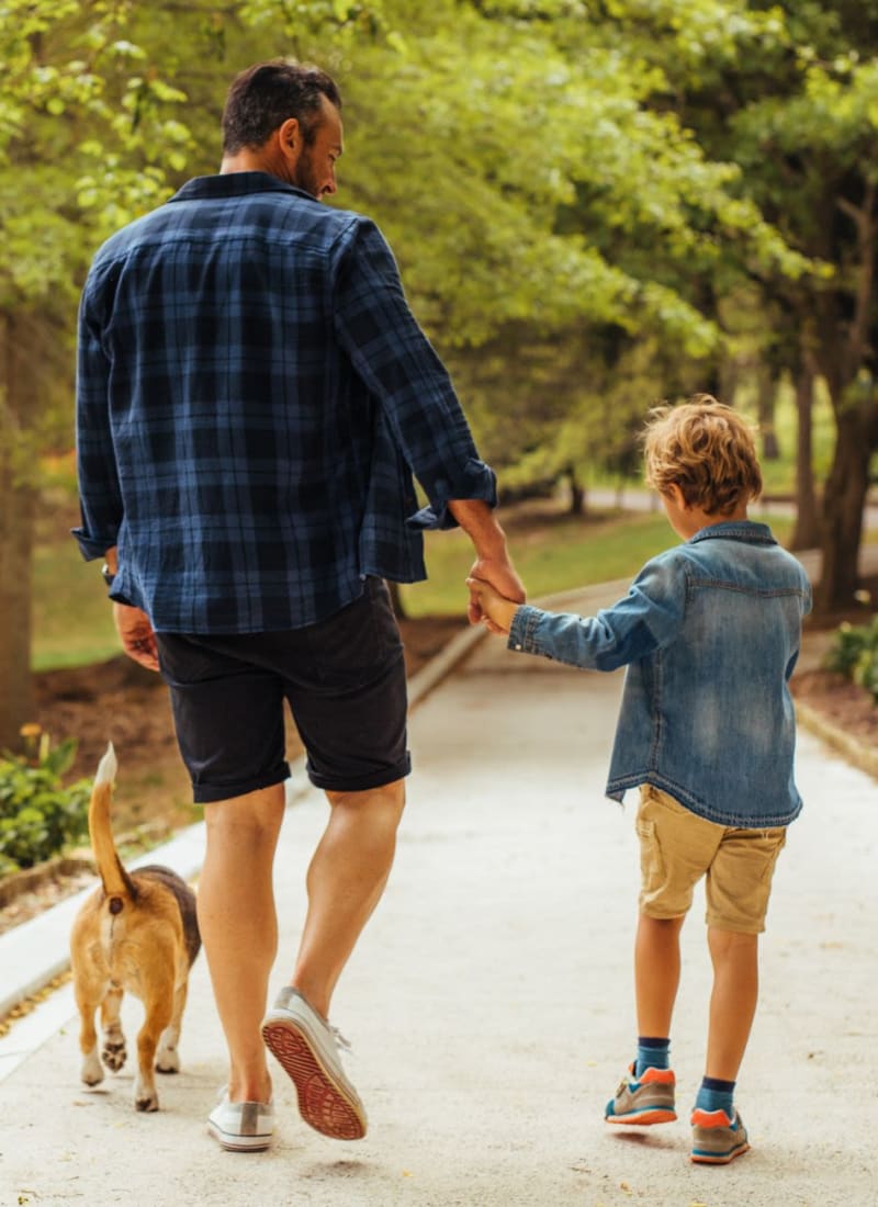 Dad and son walking their dog near Marquis Ellis Crossing in Durham, North Carolina