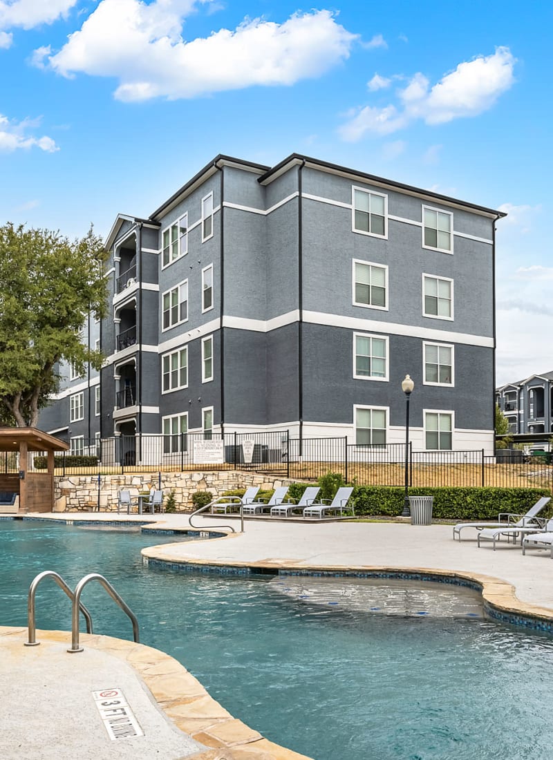 Lit pool at sunset in front of units at Marquis at Crown Ridge in San Antonio, Texas