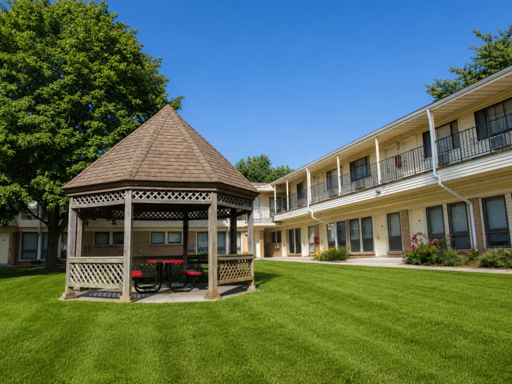 Gated community with a gazebo and picnic area surrounded by lush green grass and trees at South Oak in Ames, Iowa