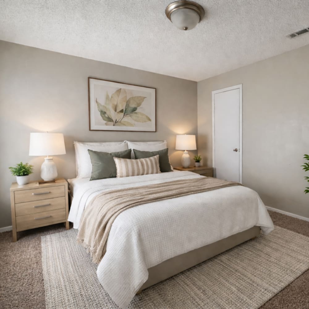 Cozy bedroom with a large bed at Amelia Apartments and Townhomes in Valdosta, Georgia