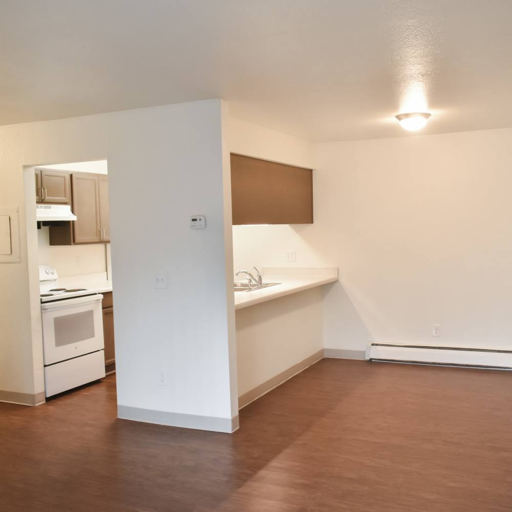 Unfurnished living room with a view to kitchen and wood-style flooring at Lakewood Apartments in Stockbridge, Michigan