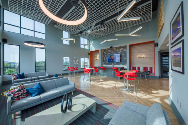 Industrial style clubhouse with sleek furniture and vaulted ceilings with hanging fixtures at a property by  WRH Realty Services, Inc 