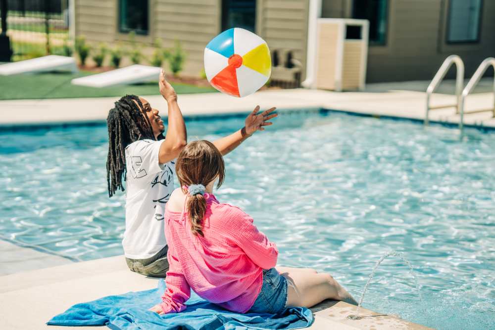 Residents on the edge of a pool with a ball at The Waters at Promenade in Marrero, Louisiana