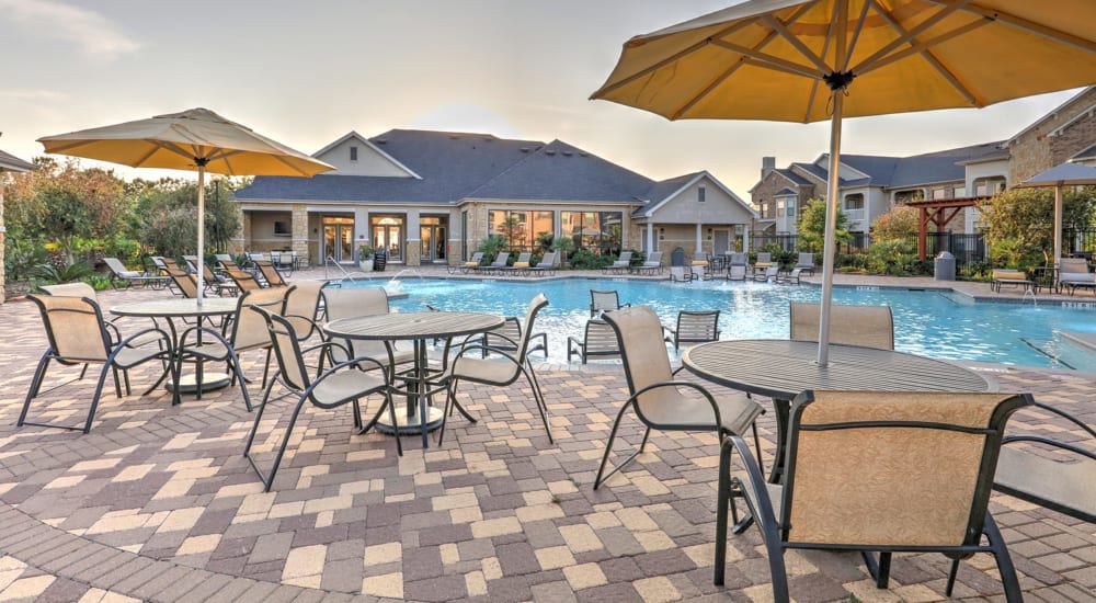 Patio tables and chairs surround the pool at Waterstone at Cinco Ranch in Katy, Texas