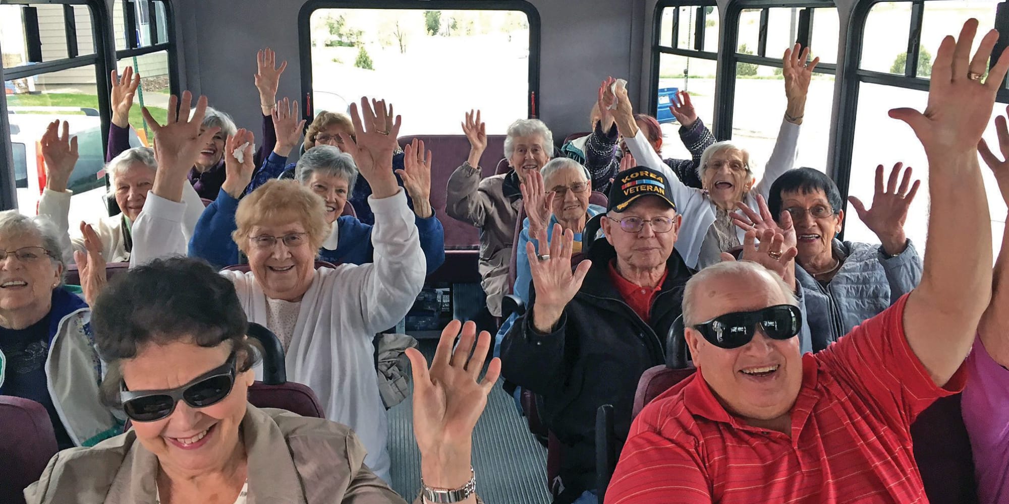 Resident from Summit Glen in Colorado Springs, Colorado with their hands up in the community bus