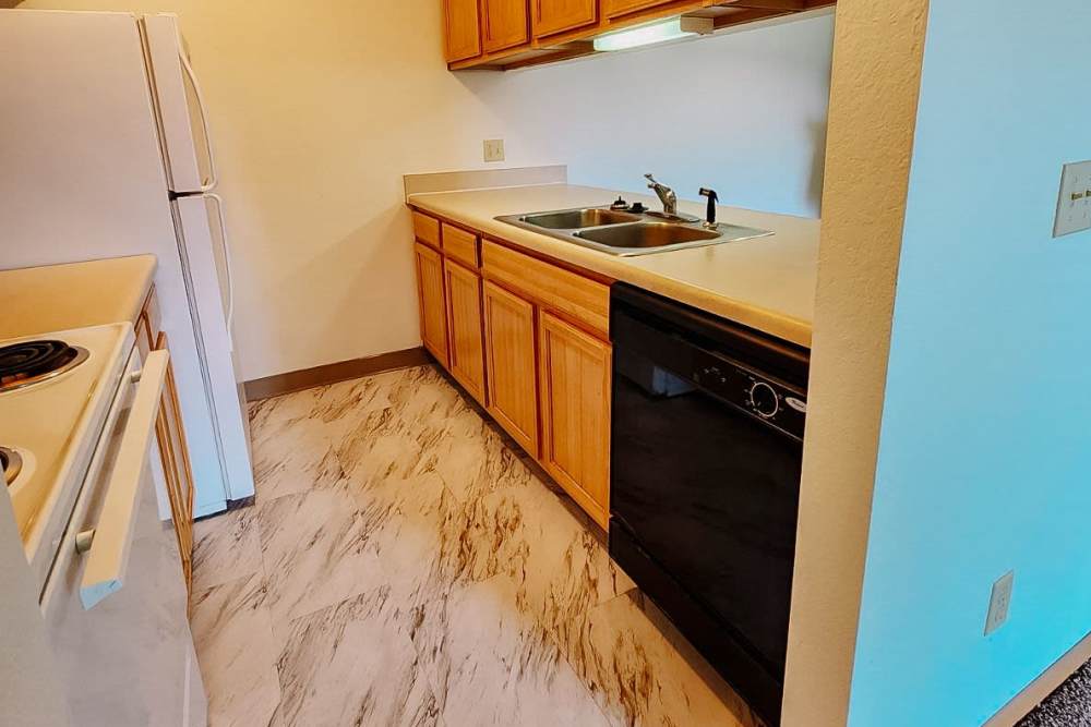 Kitchen with refrigerator, wooden cabinets, microwave, and dishwasher at Rivercrest Apartments in Croswell, Michigan
