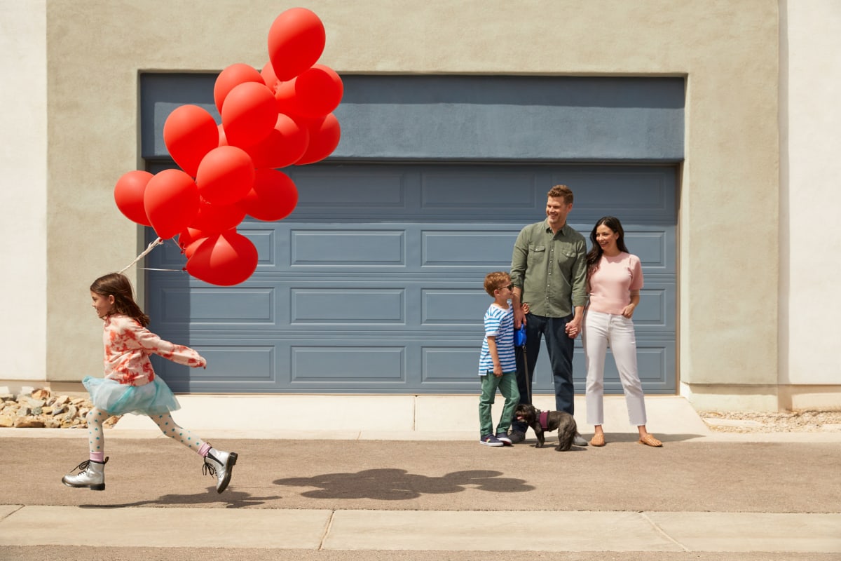 A girl running with a bunch of balloons with her family at BB Living at Civic Square in Goodyear, Arizona