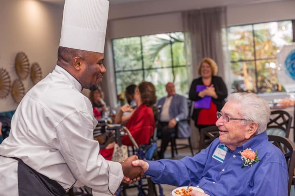 A resident shaking hands with the chef at Atrium at Liberty Park in Cape Coral, Florida