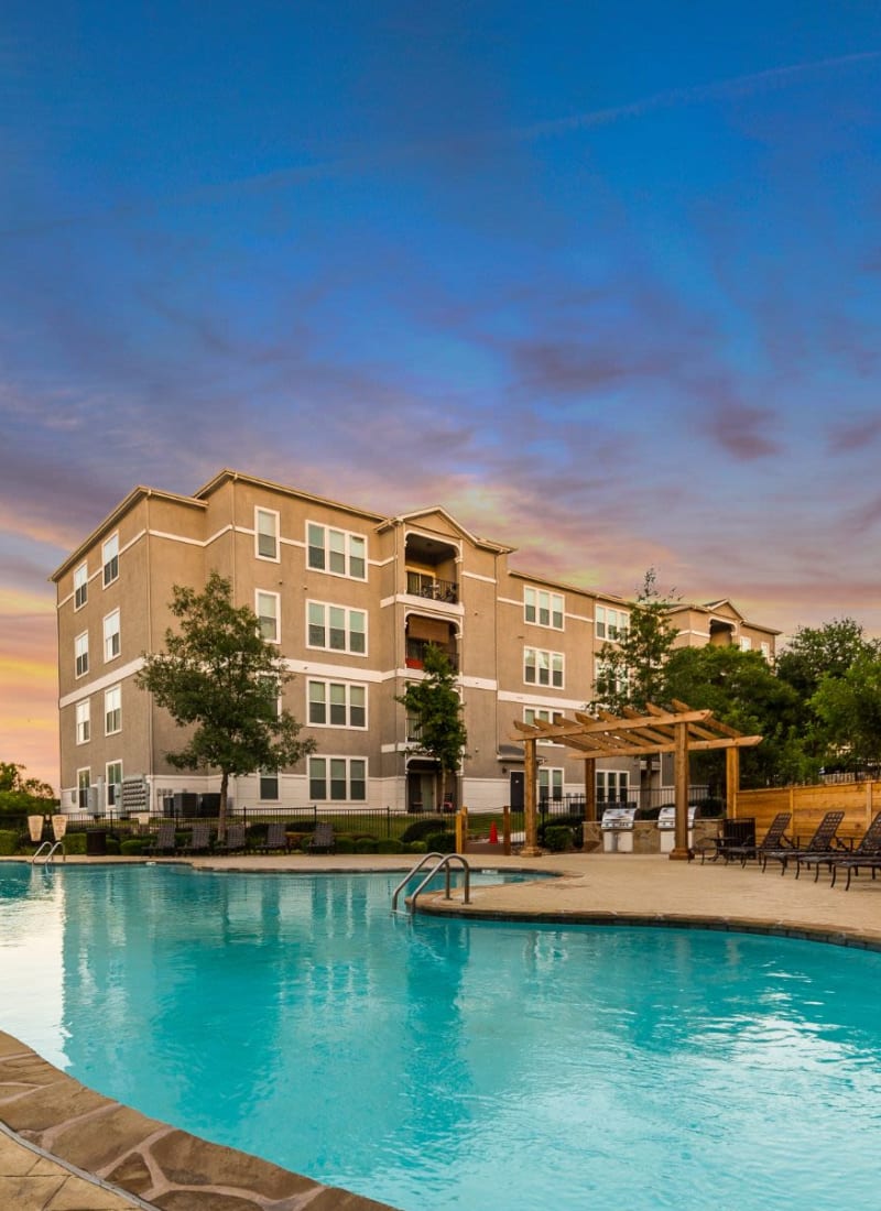 Lit pool at sunset in front of units at Marquis at Crown Ridge in San Antonio, Texas