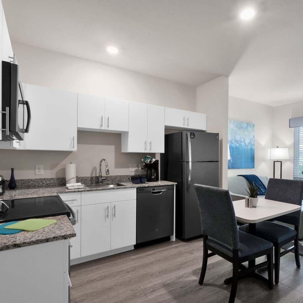 Fully equipped kitchen with granite countertop stainless steel appliances and view of living room at WaterWalk Charlotte - Arrowood in Charlotte, North Carolina