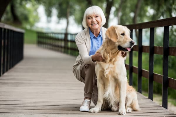 Senior woman on a bridge with her golden retriever at The Pillars of Hermantown in Hermantown, Minnesota