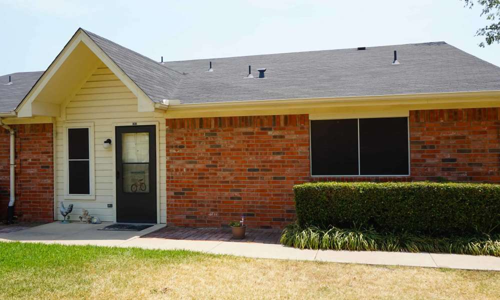 Charming brick facade with inviting front porch and green lawn at The Parc at Bakers Pointe in Richland Hills, Texas