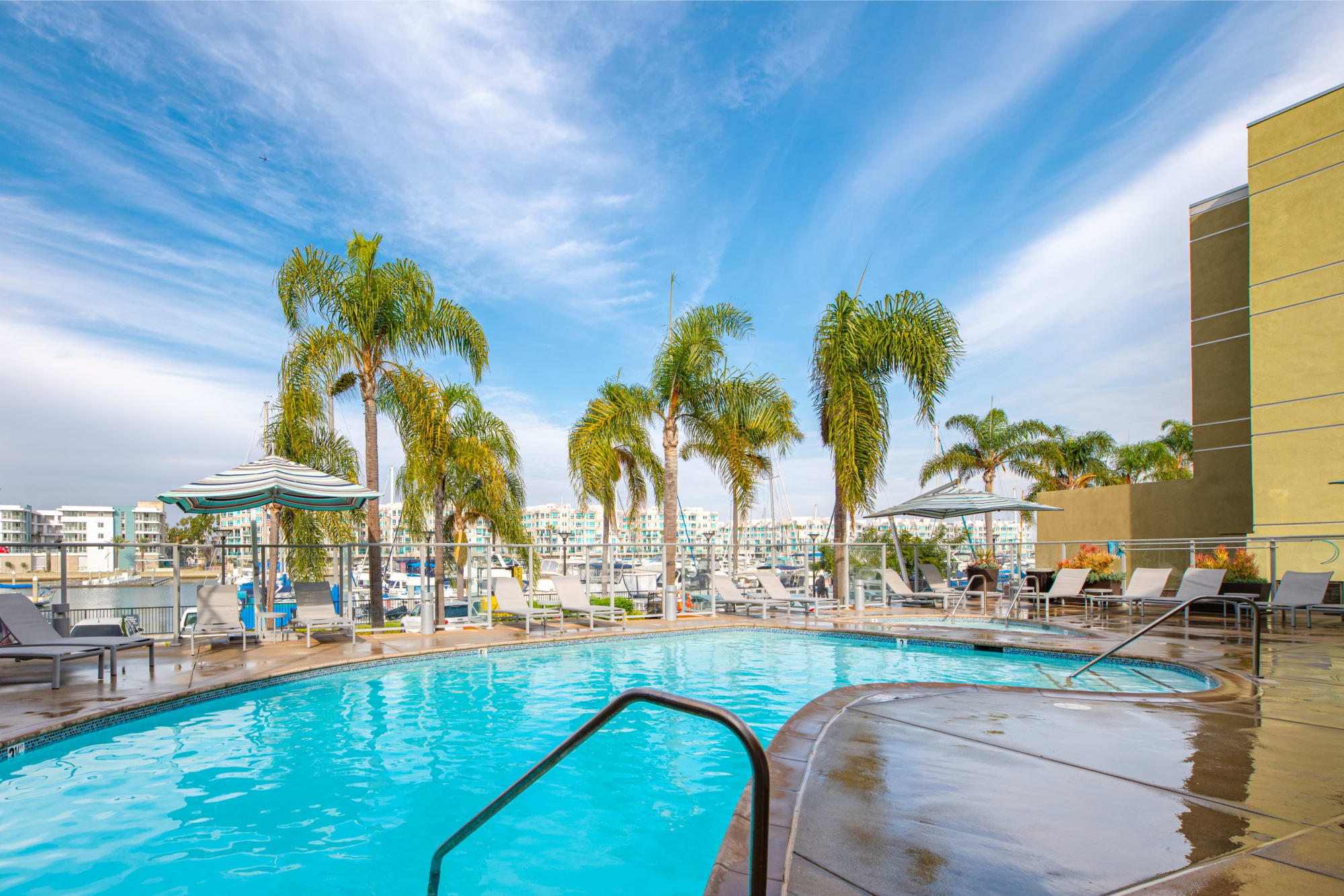 The pool and palm trees on a beautiful day at Harborside Marina Bay Apartments in Marina del Rey, California