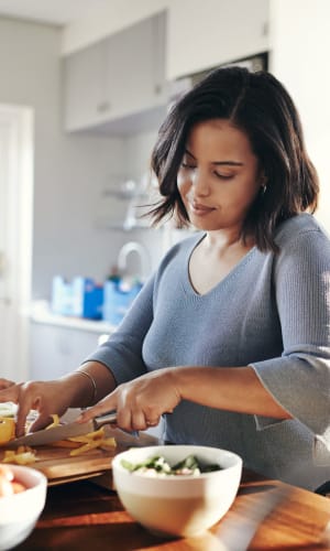 Resident chopping vegetables for a fresh meal in her kitchen at Vista Park in Dallas, Texas