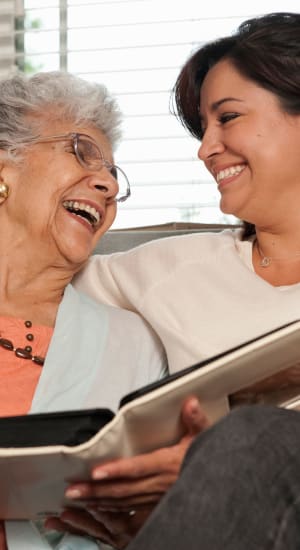 Resident and lady looking at a photo album at Heritage Senior Living in Blue Bell, Pennsylvania