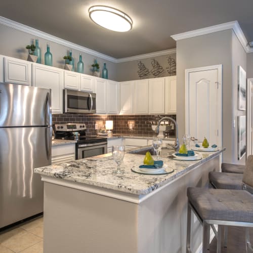Gourmet kitchen with an island and subway tile backsplash in a model home at Olympus Las Colinas in Irving, Texas