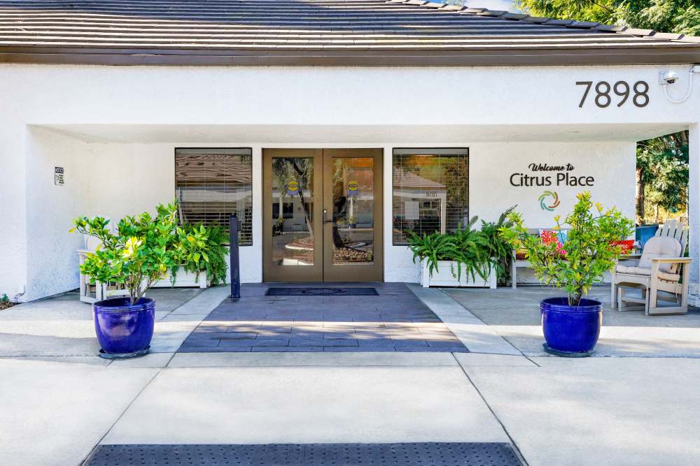 Front entrance of Citrus Place with white exterior, potted plants, and the building number 7898 displayed above the doorway at Citrus Place in Riverside, California