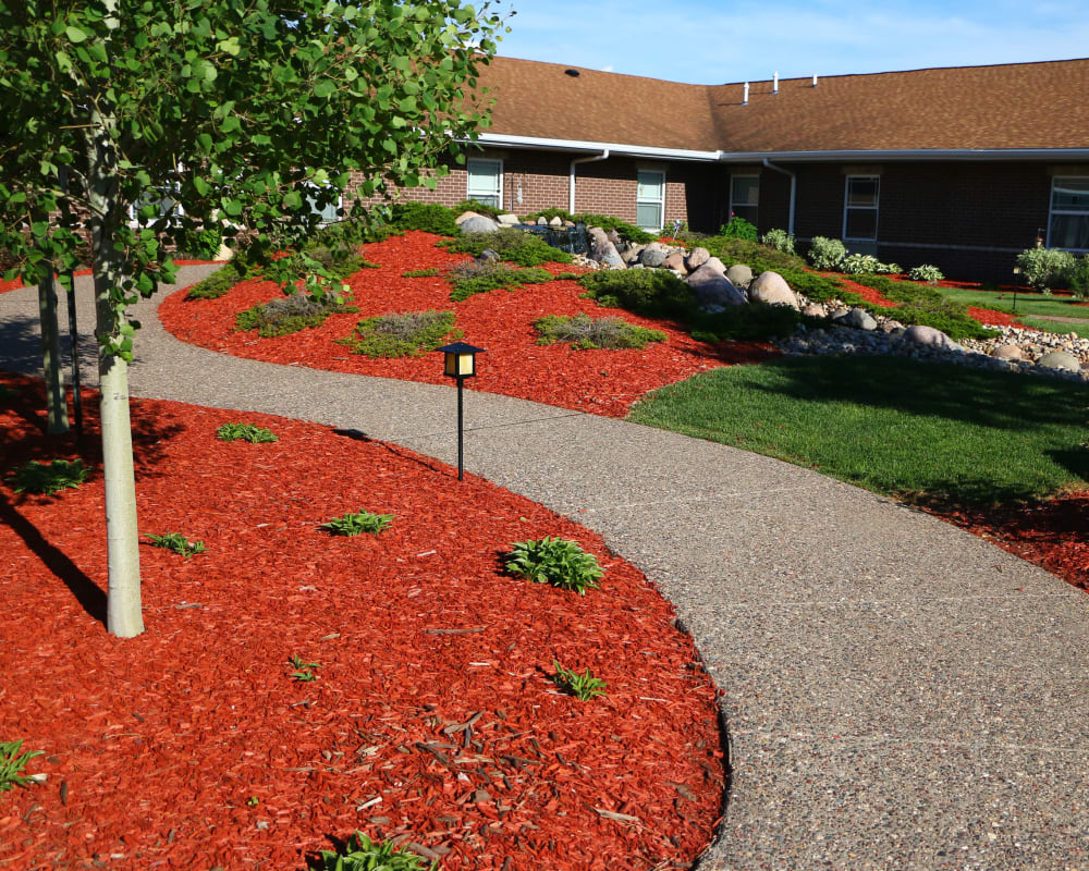Inviting walking path through lush landscaping at Addington Place of Clinton in Clinton, Iowa.