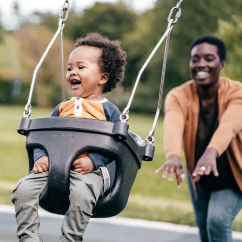 Resident pushing her child on a swing at Orchard Park, Edgewater Park, New Jersey