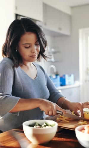 Resident preparing a meal in her new kitchen at Highlands of Duncanville in Duncanville, Texas