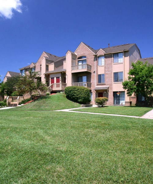 Brick apartment building and lush lawn at Saddle Creek Apartments in Novi, Michigan