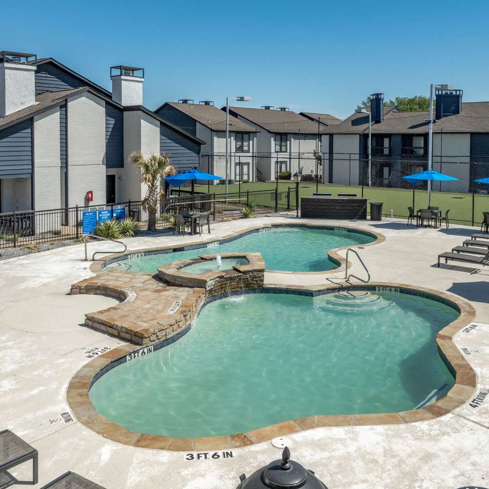 Resort-style swimming pool with lounge chairs and view to the community building at The Linden Apartments in Dallas, Texas