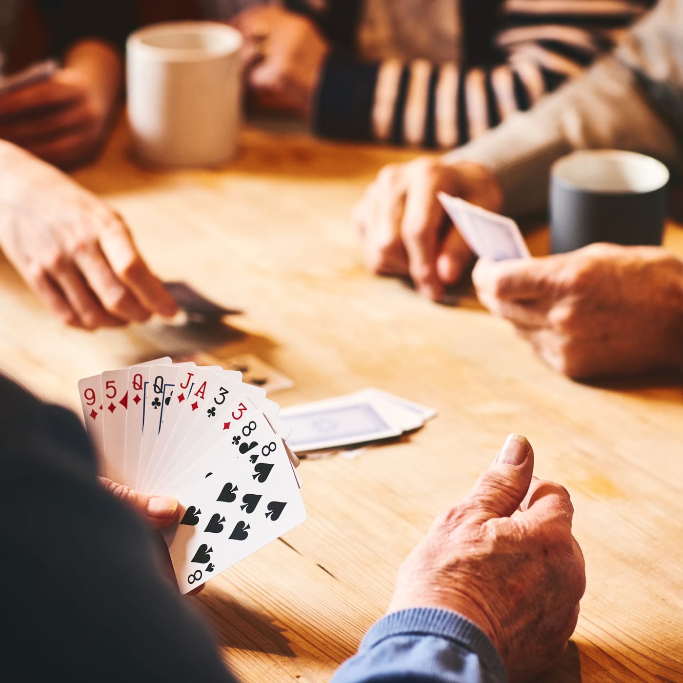 Senior man playing cards with friends in Silver Spring, Maryland at The Oaks at Four Corners