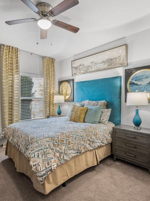 Elegant model master bedroom with carpet flooring and a ceiling fan at The Residences at Panther Hollow in Marble Falls, Texas