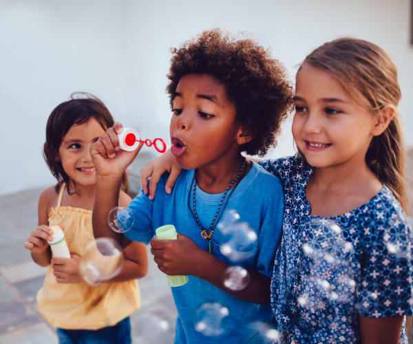 Children blowing bubbles outside at Wheeler Terrace in Washington, District of Columbia